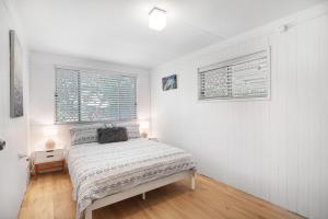 a white bedroom with a bed and two windows at Billa Bungalow - 16 Billa Street in Point Lookout