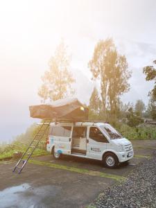 un furgone bianco parcheggiato in un parcheggio con tenda di Campervan Bali Rental a Dalung