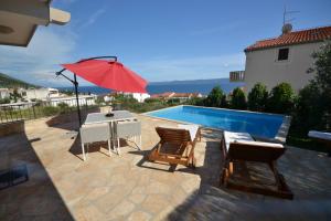een zwembad met een tafel en stoelen en een rode parasol bij Villa Magalia in Bol