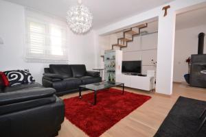 een woonkamer met een zwarte bank en een rood tapijt bij Villa Magalia in Bol