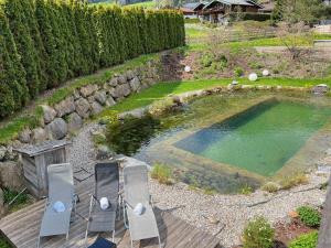 un patio con 2 sillas y una piscina de agua en HIDEAWAY DESIGN CHALET by Belle Stay en Kitzbühel