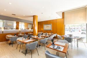a restaurant with wooden walls and tables and chairs at Catalonia Gran Hotel Verdi in Sabadell