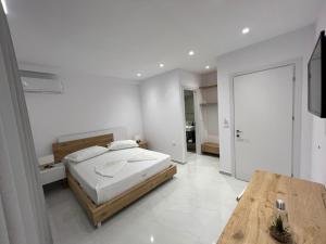 a white bedroom with a bed and a wooden table at Sea Breeze Villa in Sarandë