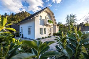 a white house with a balcony and plants at Vila Mignon in Bled