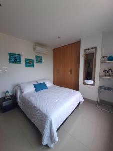 1 dormitorio con cama blanca y armario de madera en Bello Horizonte * Unido Al Mar, en Santa Marta