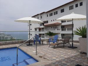 a pool with chairs and umbrellas next to a building at Bello Horizonte * Unido Al Mar in Santa Marta