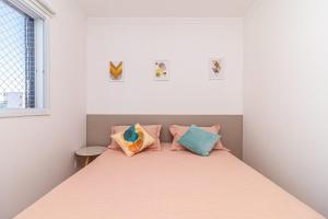 Dormitorio pequeño con cama con almohadas coloridas en Aptos na PG em excelente localização à 100m da PRAIA no Centro da Cidade com Garagem, Ar Condicionado, Portaria 24H en Praia Grande
