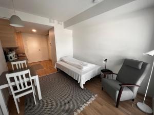 a small bedroom with a bed and a chair at Kotimaailma Apartments - Madetojanaukio in Oulu