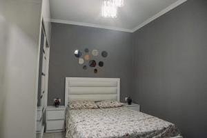 a bedroom with a white bed and a gray wall at Family apartment in Batumi