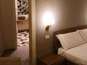 een slaapkamer met een bed en een lampje aan de muur bij Vicoli di Napoli B&B in Napels