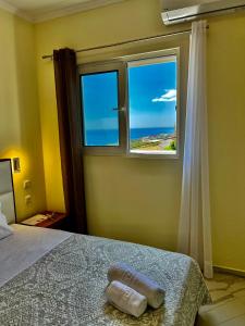 a bedroom with a bed and a window with the ocean at Oscar’s Apartments Drymades in Dhërmi