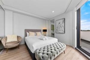 a bedroom with a large bed and a chair at Elegant and Modern Style Apartments in Dulwich hill in Sydney
