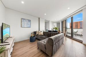 een woonkamer met een bank en een groot raam bij Elegant and Modern Style Apartments in Dulwich hill in Sydney