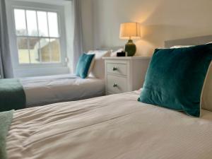 a bedroom with two beds with green pillows and a window at Wesley Cottage in Middleham