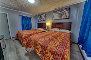 a hotel room with two beds and blue curtains at Aqua View Motel in Panama City Beach