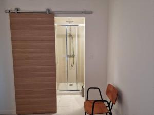 a glass shower door in a bathroom with a chair at Gîtes de l'Estagnol in Villeneuve-lès-Maguelonne +22 photos