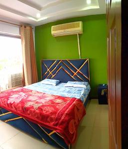 een slaapkamer met een bed en een groene muur bij Comfortable Rental Apartments In Bahria Town in Rawalpindi