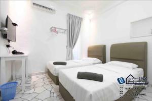 a room with two beds and a tv in it at Cozy 6BR Gurney GeorgeTown Homestay in Tanjung Bungah