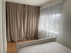 ein Schlafzimmer mit einem weißen Bett und einem Fenster in der Unterkunft Cozy apartment near TalTech and Elamus SPA in Tallinn