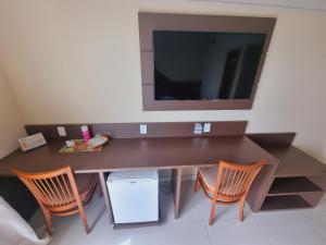 a room with a desk with chairs and a television at Tropical Executive Flat Vista Incrível para a Orla in Manaus
