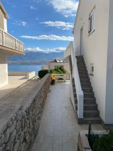 Una escalera que conduce a un edificio blanco con una pared de piedra. en Apartmani Požega, en Pag