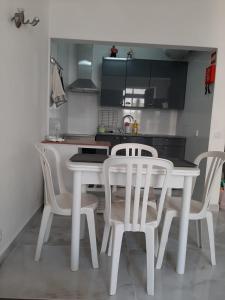 a kitchen with a white table and white chairs at Casa da Praia in Armação de Pêra