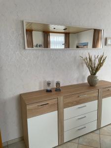 a wooden dresser with a mirror on a wall at In't Noord in Tossens
