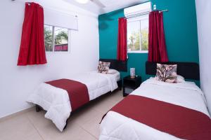 2 camas en una habitación con cortinas rojas y paredes verdes en EDMA APARTAHOTEL, en Santa Bárbara de Samaná