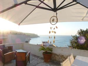 un patio con una mesa y una sombrilla y el océano en Casa Vacanze Vincenzo e Rosanna, en Castro di Lecce