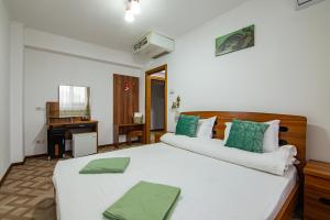 una camera da letto con un grande letto bianco con cuscini verdi di Pensiunea Pestisorul a Dunavăţu de Jos