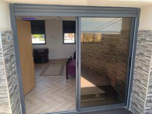 uma porta de vidro que dá para um quarto com uma parede de tijolos em El mar beach 2 em Moulay Bousselham