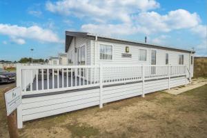 a white mobile home with a white fence at Beautiful 8 Berth Lodge For Hire At Kessingland Beach In Suffolk Ref 90012td in Benacre