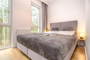 梅爾諾的住宿－Domki - Villa Buena Vista - Mielno，一间卧室设有一张大床和两个窗户。