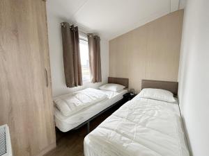 a bedroom with two beds and a window at Chalet 527 op Recreatiepark De Wielen in Sint Maarten +21 photos