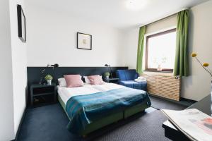 a bedroom with a bed and a chair and a window at City Hotel Fellbach 24H CHECK-IN in Fellbach