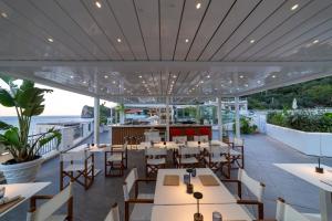 un ristorante con tavoli e sedie bianchi e vista sull'oceano di Punta Campanella Resort & Spa a Massa Lubrense