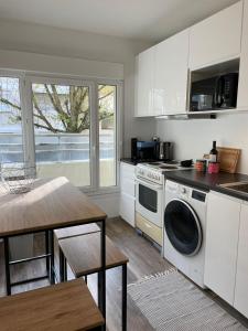 cocina con lavadora y mesa en Appartement SQY en Guyancourt