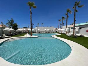 a swimming pool with palm trees in a resort at ON City Apartments in Matalascañas