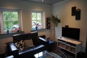 ein Wohnzimmer mit einem Ledersofa und einem Flachbild-TV in der Unterkunft Guesthouse Rijsbergen_Zundert in Zundert