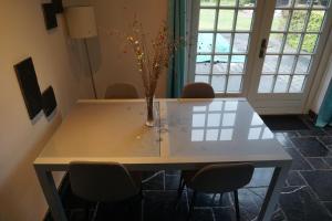 Guesthouse Rijsbergen_Zundert في Zundert: طاولة عليها مزهرية مع كراسي حولها