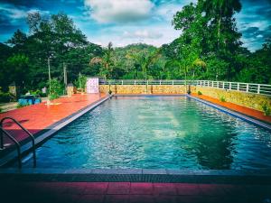 uma piscina de água com cerca e árvores em Capital Resort Inn em Monaragala