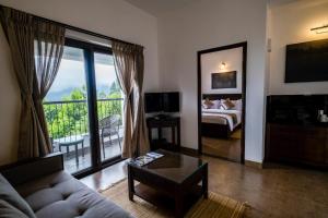 d'un salon avec un canapé et un lit ainsi que d'un balcon. dans l'établissement Dvara Luxury Resort Kodaikanal, à Kodaikānāl