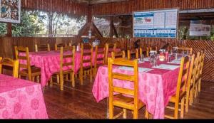 Caiman Lodge في Cuyabeno: مطعم بطاولات وكراسي مع طاولة قماش وردية