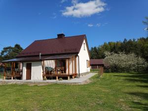 a small white house with a picnic table in a yard at Agroturystyka Sosnowy Gaik in Tykocin
