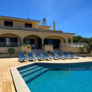 une villa avec une piscine, des chaises et une maison dans l'établissement Villa Paraiso - 4 Bedrooms and pool, à Albufeira