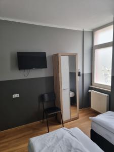 una camera da letto con TV, sedia e specchio di Hotel Fly ´ In a Offenbach