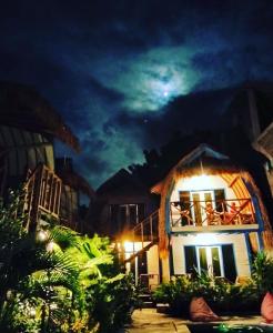 a house at night with the moon in the sky at Tropical House Bungalows in Gili Trawangan