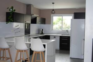 a kitchen with white appliances and white stools at AC Interlude in Castelnau-de-Montmiral