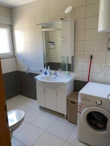 a bathroom with a sink and a washing machine at Apartment 28 in Ljubuški +18 photos