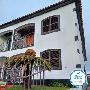 Casa blanca con ventanas marrones y valla en Alves Nature Rooms en Arrifes